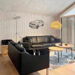 Wohnzimmer mit schwarzen Sofas, Holzmöbeln und Wanddekoration.