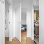 Flur mit Blick in Schlafzimmer und Badezimmer. Holzboden und weiße Wände.