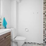 Badezimmer mit Waschbecken, Toilette und Dusche mit Mosaikfliesen.