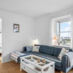 Wohnzimmer mit Sofa, Couchtisch und Blick auf Hafen. Schlafzimmer ist angrenzend.