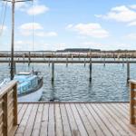 Holzterrasse mit Blick auf Hafen und Boot.