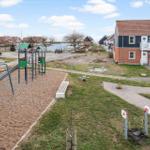 Kinderspielplatz mit Rutsche und Schaukel neben einem Haus mit rotem Dach.