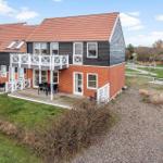 Zweistöckiges Ferienhaus mit Balkon, Terrasse und Garten. Rotes Dach und weiße Geländer.