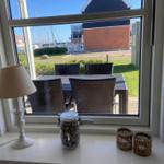 Durch das Fenster ist ein Garten mit Tisch und Stühlen zu sehen.