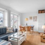 Wohn- und Essbereich mit Sofa, Tisch und TV. Durchgänge zu Balkon und Küche.