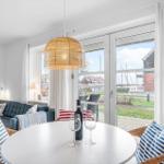 Ein Essbereich mit runden Tisch und Stühlen. Durch Fenster ist Blick auf Außenbereich.