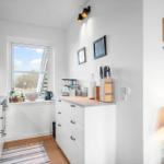 Küche mit Fenster, weißen Schränken und Küchenutensilien an der Wand.