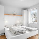 Schlafzimmer mit Bett, weißen Schränken und Fensterblick.