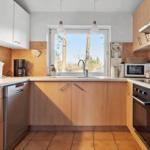 Küche mit Holzschränken, Spüle und Fensterblick auf Bäume