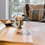 Ein Raum mit Sessel, Kissen und Fensterblick auf Wald.