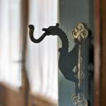 Antik wirkender Haken in Form eines Drachen an einer Tür.