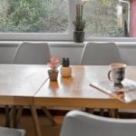 Esstisch mit Stühlen vor großem Fenster mit Blick auf Wald.