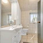 Badezimmer mit Waschbecken, Toilette und Dusche. Fenster mit Blick auf Bäume.