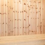 Holzwand mit Sitzbank und Eimer in Sauna