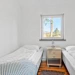 Zwei Einzelbetten, Nachttisch und Fenster mit Blick auf Bäume.