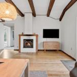 Wohnzimmer mit Kamin, Fernseher und Holzboden.