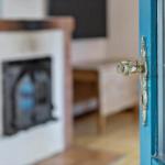 Tür mit Metallgriff führt in einen Raum mit Kamin und Fernseher.