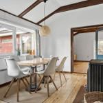 Esszimmer mit Holzboden, Tisch und Stühlen, Fenster und Durchgang.