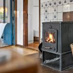 Holzofen mit brennendem Feuer an Wand mit Schiffstapeten.