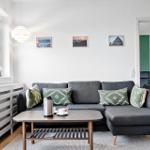 Ein Wohnzimmer mit grauem Sofa, Holztisch und Fensterblick.