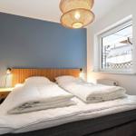 Schlafzimmer mit Doppelbett, blauer Wand und Fensterblick.