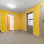 Flur mit gelben Wänden, Lift und Türen zu Wohnungen.