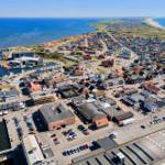Aerial view of coastal town with harbor, beaches, and residential areas.