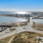 Hafenstadt mit roten Häusern, Straßenkreuzung und Blick aufs Meer.