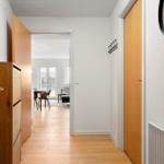 Flur mit Holztüren und -möbeln, Blick in Essbereich mit Tisch und Stühlen.