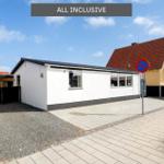 Wohnhaus mit Garage und gepflastertem Weg unter blauem Himmel.