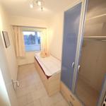 Schlafzimmer mit Bett, Kleiderschrank und Fenster mit Vorhängen.