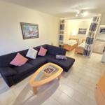 Wohnbereich mit Sofa, Couchtisch und Blick in Schlafzimmer und Küche.