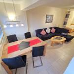 Wohn- und Essbereich mit Sofa, Tisch und zwei Betten im Hintergrund.