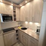 Küche mit Holzschränken, Herd, Spüle und Kaffeemaschine.