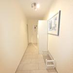 Flur mit weißem Kleiderständer, Bild an der Wand und Licht an der Decke.