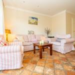 Wohnzimmer mit Streifensofa, Holztisch und Fliesenboden.