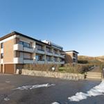 Modernes Mehrfamilienhaus mit Balkonen und Garage. Hinterhof mit Steig und Schneeresten.