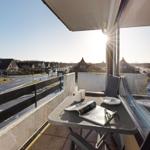 Terrasse mit Tisch, Stühlen und Blick auf Straße und Häuser.