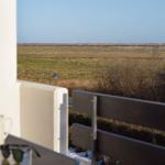 Blick von Balkon auf weites Grasland mit Bäumen und Ferne.