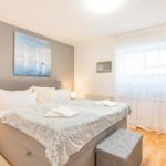 Schlafzimmer mit Bett, Fenster und Wandbild. Holzboden und Vorhänge.