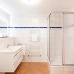 Badezimmer mit Dusche, Waschbecken und Heizkörper