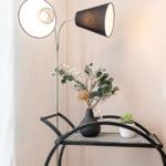 Hochwertige Stehlampe neben einem Tisch mit Pflanzen und Dekoration.