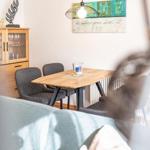 Essbereich mit Holztisch, Stühlen und Glasvitrine an der Wand.
