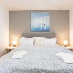 Schlafzimmer mit Doppelbett, Wandbild und Nachttischen mit Lampen.