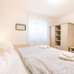 Schlafzimmer mit Bett, Kleiderschrank und Fernseher an der Wand.