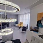 Wohnzimmer mit moderner Deckenleuchte, Sitzgelegenheiten und Wandbildern.