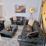 Wohnzimmer mit schwarzen Ledersofas, goldfarbenen Lampen und abstrakten Wandbildern.