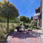 Außenbereich mit Tisch und Stühlen auf Steinplatten neben einem Gebäude.