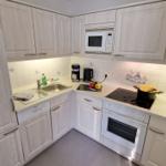 Küche mit weißen Schränken, Spüle, Herd und Mikrowelle.