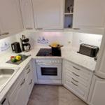 Küche mit weißen Schränken, Marmorarbeitsplatte und Edelstahlspüle.